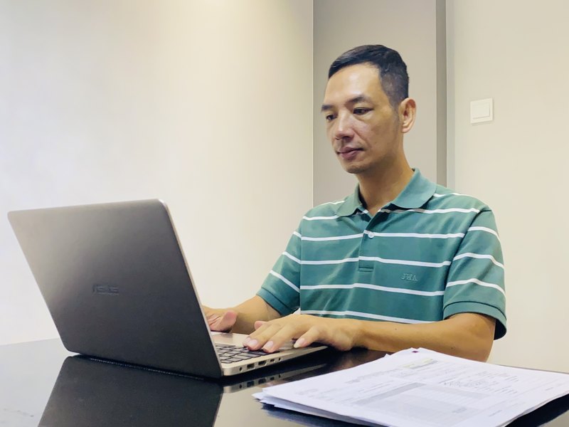 Ngồi xem hồ sơ, giấy tờ bên máy tính trước chuyến đi