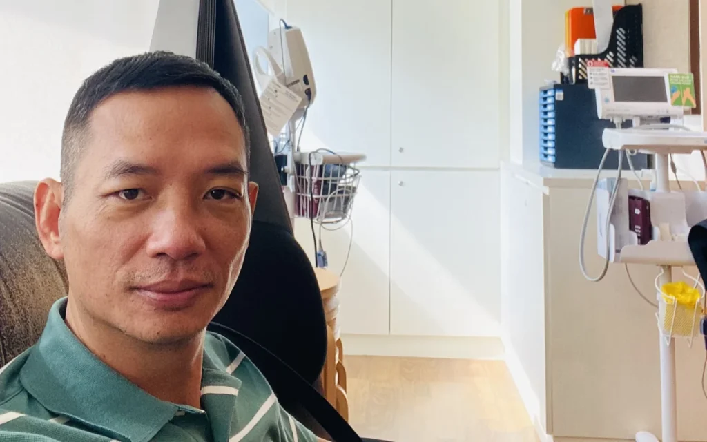 Toàn Lộc ngồi trong phòng điều trị tại bệnh viện ở Singapore