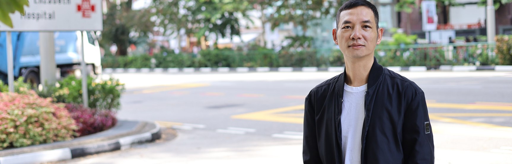 Toàn Lộc đứng trên đường phố Singapore, gần khu bệnh viện